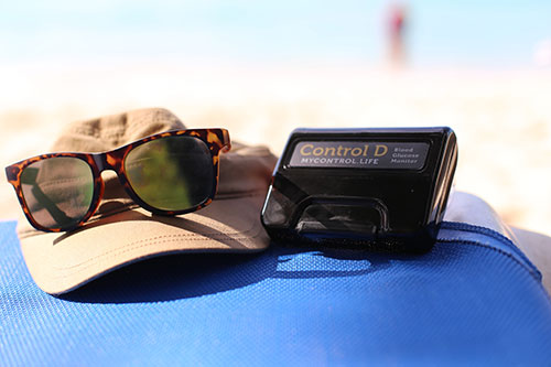 Hat and sunglasses next to a glucose reader