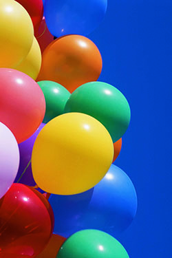 Un racimo de globos de color con un fondo de cielo azul.