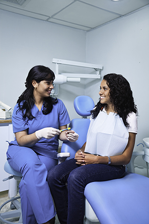 Dental healthcare provider talking to woman in exam room.