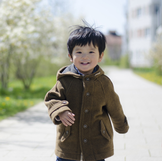 2 year old running happily in a park.