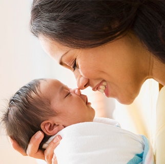 A mother holding her new born baby up to her face giving him kisses.