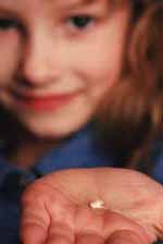Imagen de una niña pequeña que sostiene un diente en su palma.
