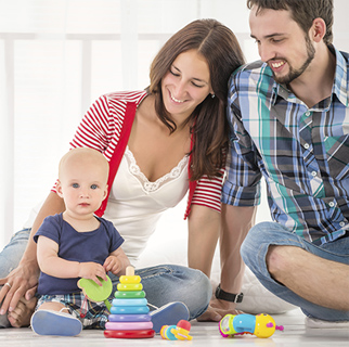 Parents sitting on the floor watching their baby playing with baby safe toys.