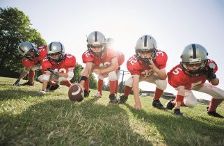 Six children in football gear in position to play