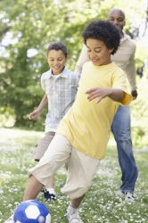 Niños jugando al fútbol con su papá