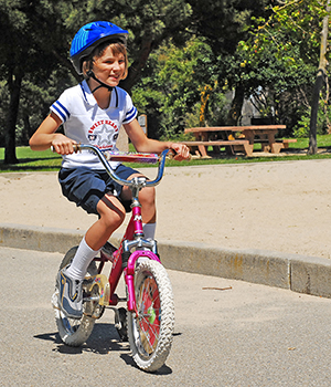 Una niña, con un casco, andando en bicicleta.