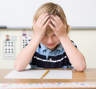 Elementary school child looking at test paper with hands to his head