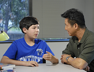 Father and son talking at table.